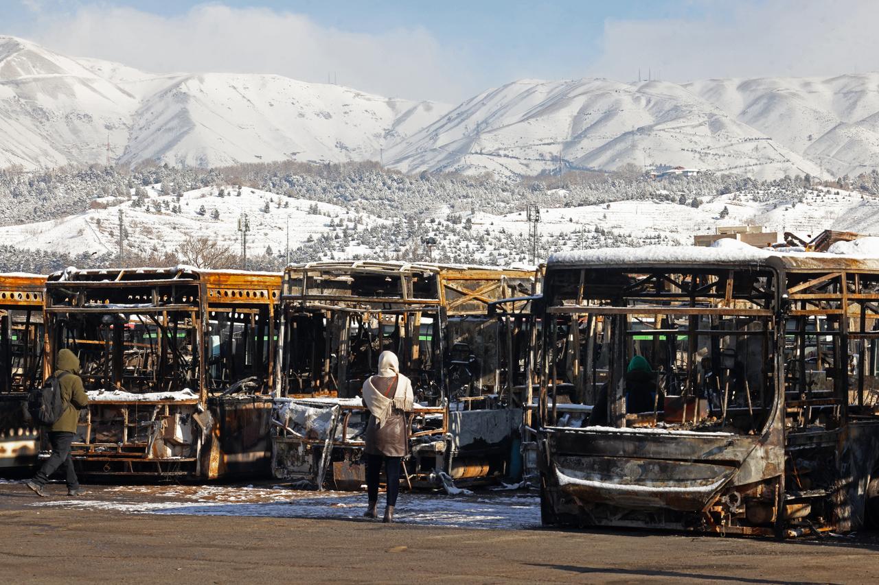 This photograph taken during a tour for foreign media shows media representatives walking past the parked buses that were burnt at a depot during recent public protests, in Tehran, Jan. 21, 2026. (AFP Photo)