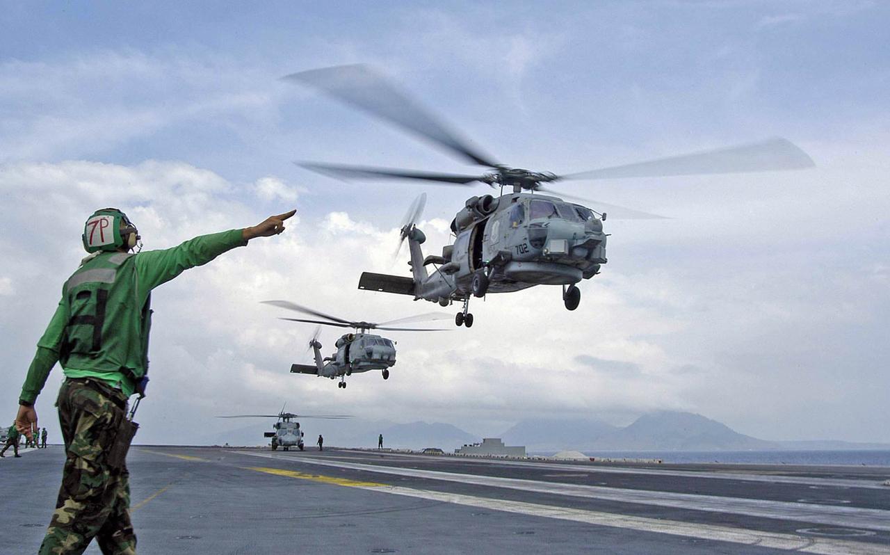 Helicopters depart from Abraham Lincoln en route to Aceh, Sumatra, supporting humanitarian airlifts to tsunami-stricken coastal regions, early 2005. (Photo via Wiki Commons)