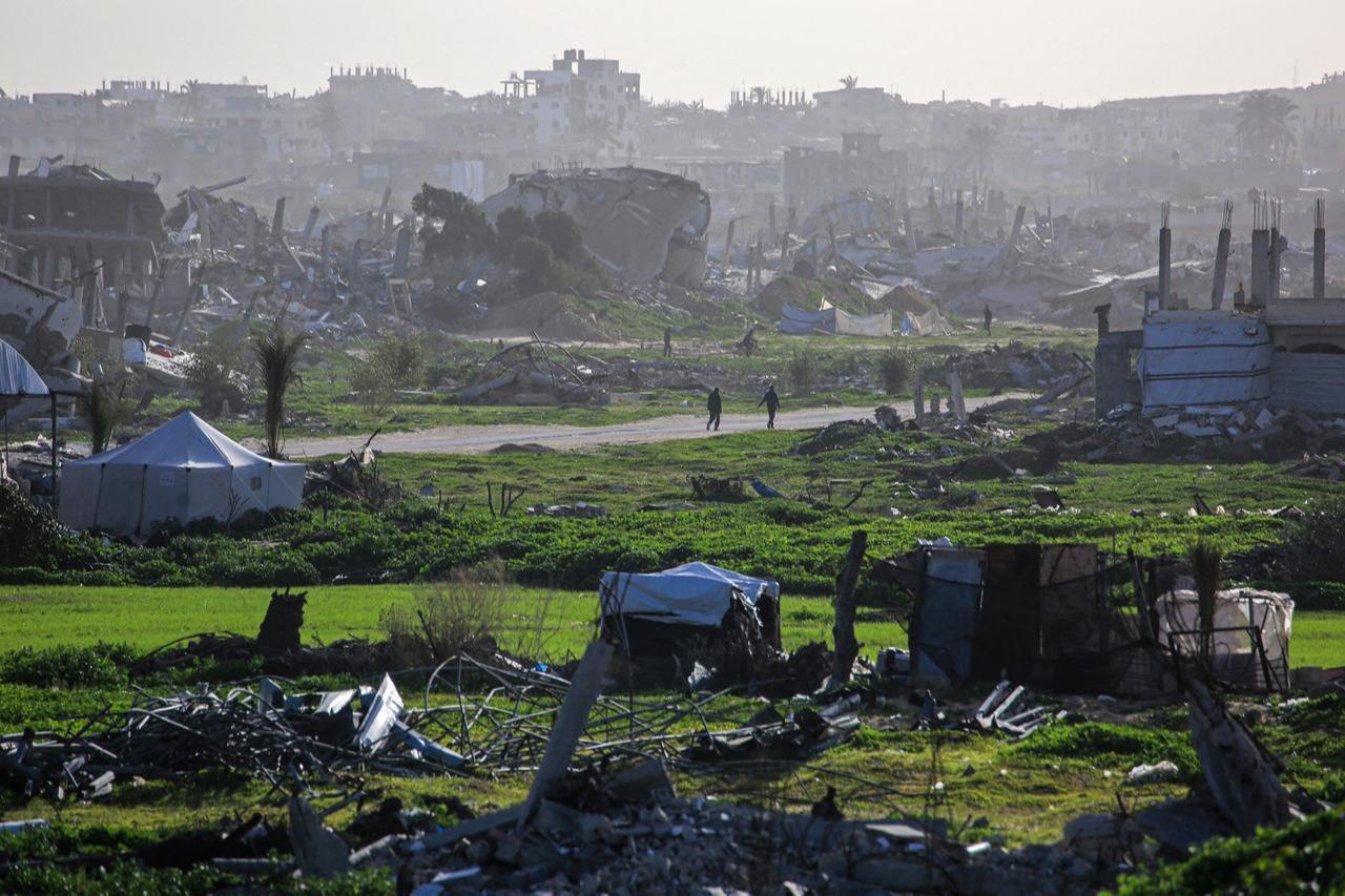 Palestinians walk along a road amid destroyed buildings in Khan Yunis, in the southern Gaza Strip, on January 25, 2026. (AFP Photo)