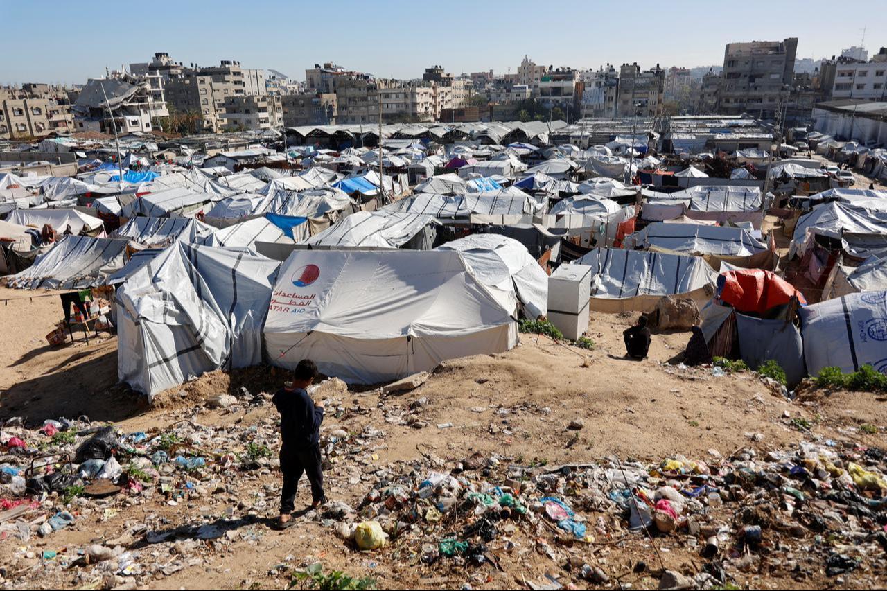 A child walks past garbage towards tent shelters housing displaced Palestinian families are set-up on empty land in Gaza City on Jan. 11, 2026. (AFP Photo)