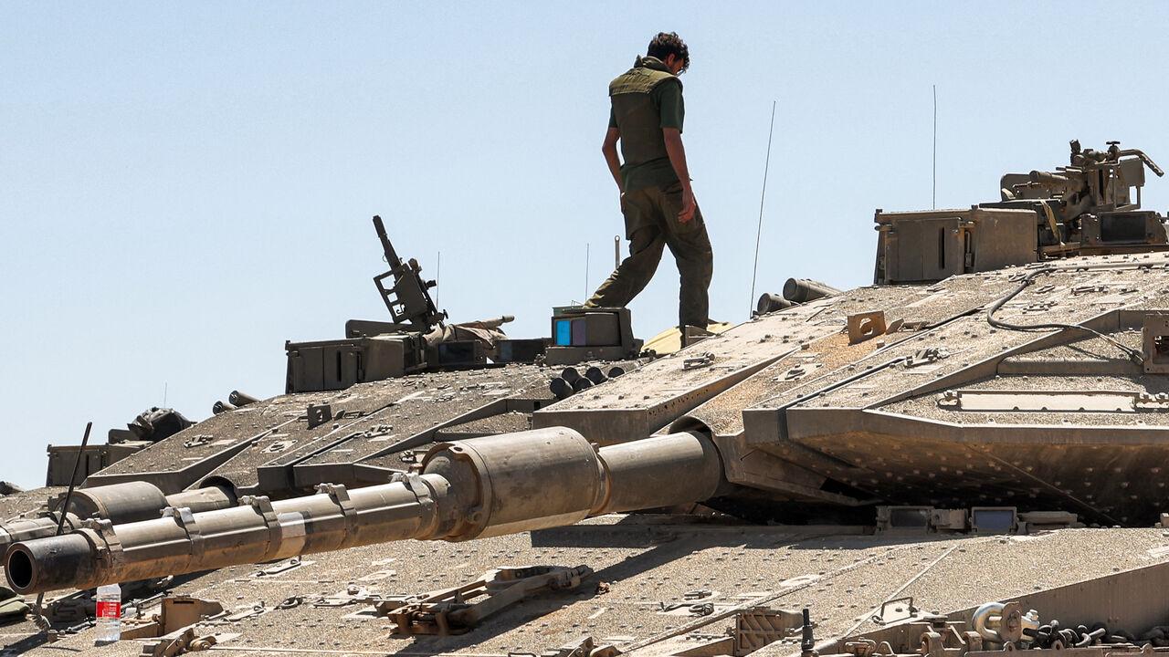An Israeli army soldier walks atop one of the main battle tanks positioned in southern Israel near the border with the Gaza Strip on May 8, 2024. (AFP Photo)