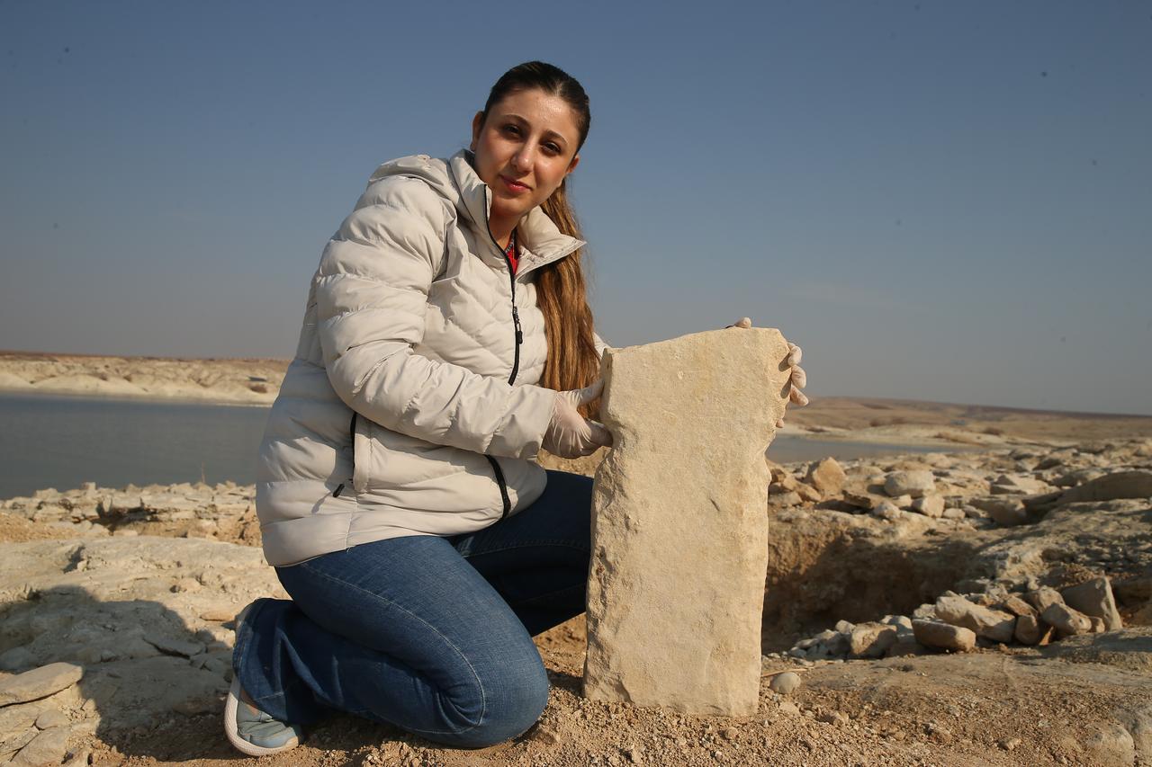 An archaeologist poses with a stone pillar believed to belong to the early Neolithic Tastelers culture during fieldwork in the Samsat district of Adiyaman, southeastern Türkiye, Jan. 27, 2026. (AA Photo)