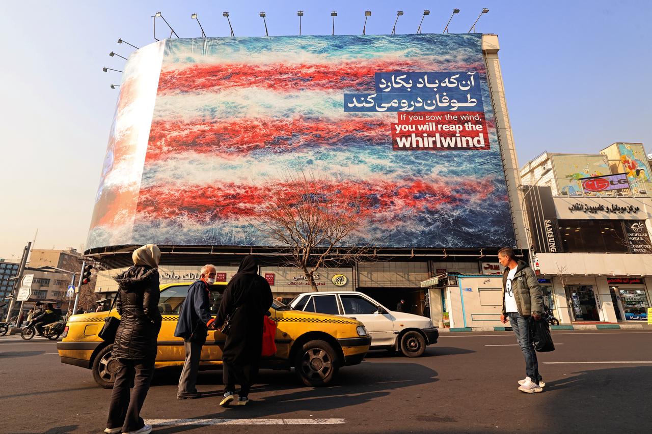 Commuters walk past an anti-US billboard installed on a building at the Enqelab Square in Tehran on January 26, 2026. (AFP Photo)
