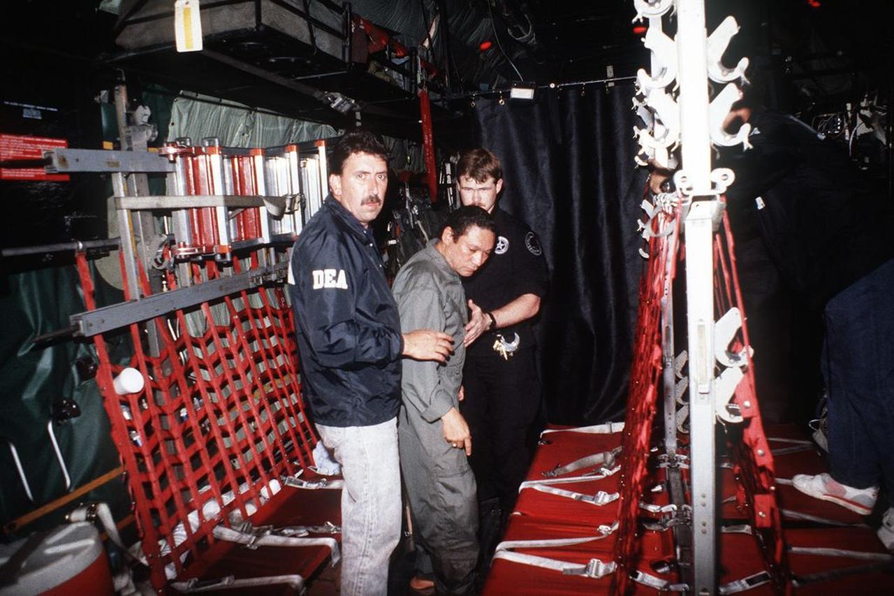 Manuel Noriega is escorted onto a US Air Force aircraft by agents from the US Drug Enforcement Agency (DEA) in 1990. (Photo via United States Air Force/Wikimedia Commons)