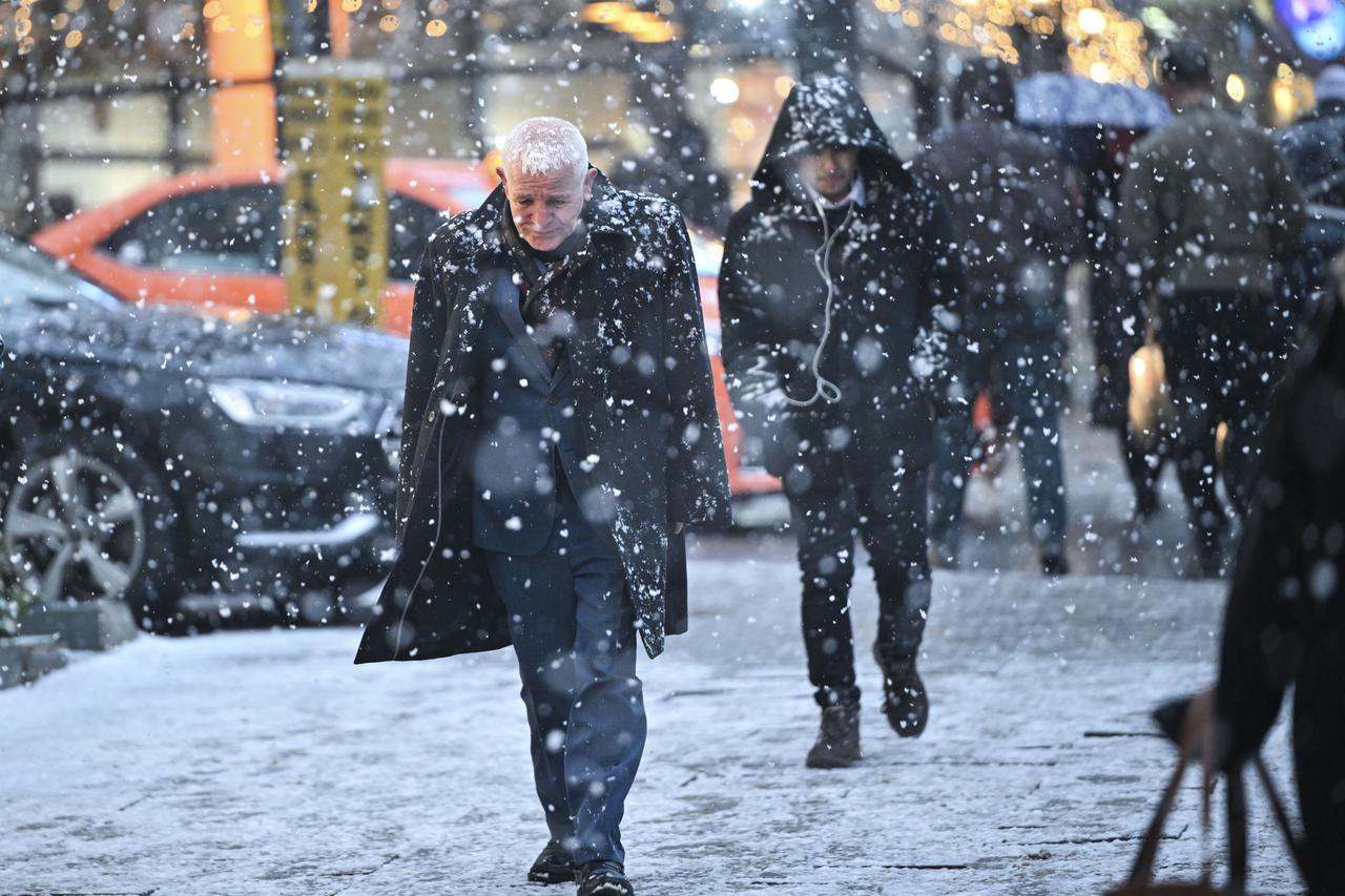 People walk on the street during snowfall in the evening hours in Ankara, Türkiye, on January 22, 2026. (AA Photo)