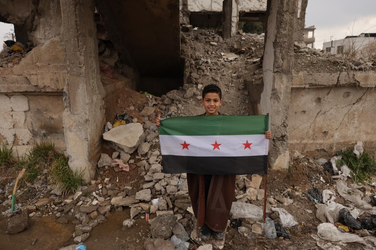 Syrian citizens are seen walking through the streets of Raqqa, Syria, holding the three-star Syrian flag on January 28, 2026. (AA Photo)