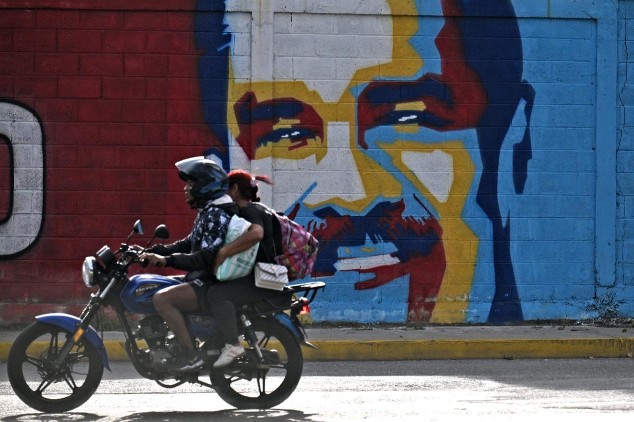 A motorcycle rides past a graffiti depicting Venezuelan President Nicolas Maduro in Caracas on Dec. 3, 2026. (AFP Photo)