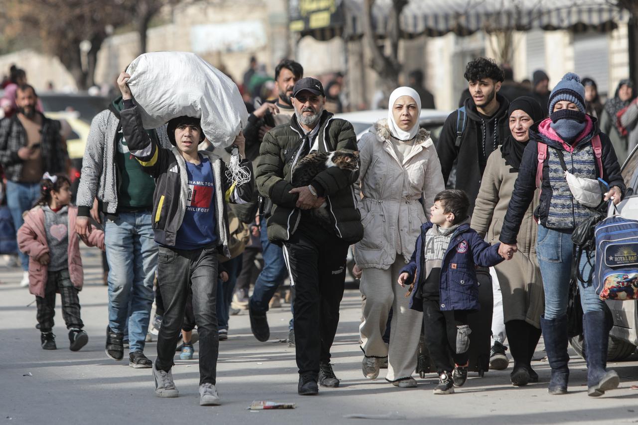 Residents carry their belongings as they flee Aleppo's Ashrafieh neighbourhood amid SDF terror group's attacks on Jan. 7, 2026.(AFP Photo)