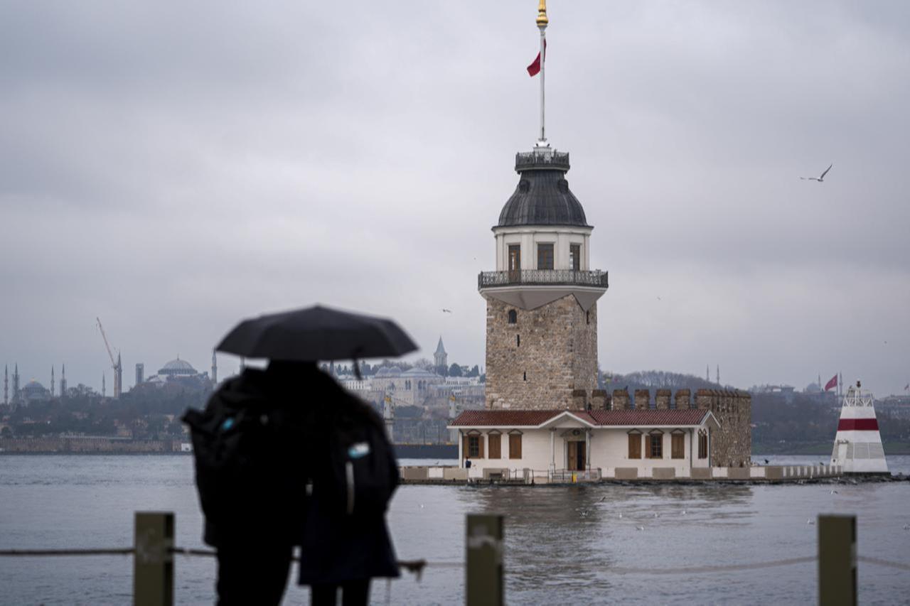 A couple trying to protect themselves from the rain under an umbrella looks towards the Maidens Tower in Uskudar district of Istanbul, Türkiye, Dec. 7, 2025. (AA Photo)