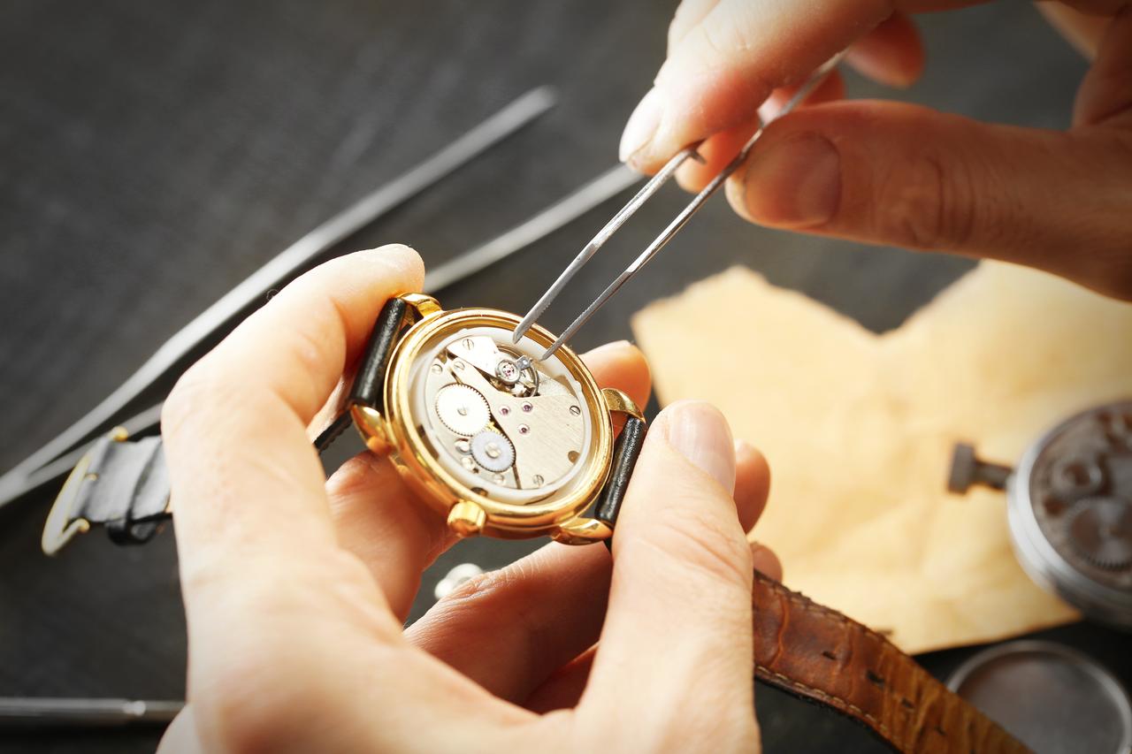 A watchmaker carefully works on the movement of a wristwatch, highlighting the precision and craftsmanship behind traditional watchmaking. (Adobe Stock Photo)