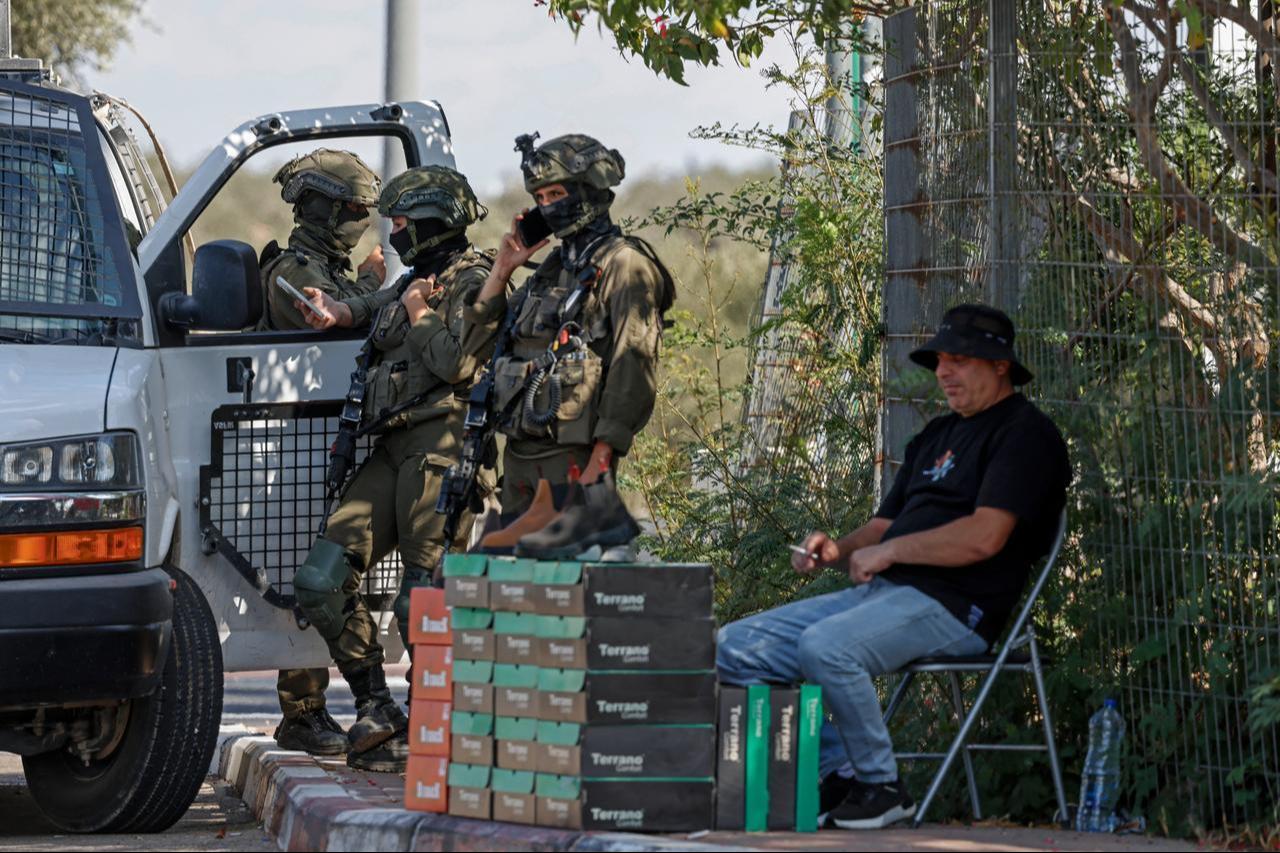Israeli soldiers stand next to a Palestinian vendor selling goods along the roadside in the village of Rantes near Ramallah, in the Israeli-occupied West Bank, Oct. 6, 2026. (AFP Photo)