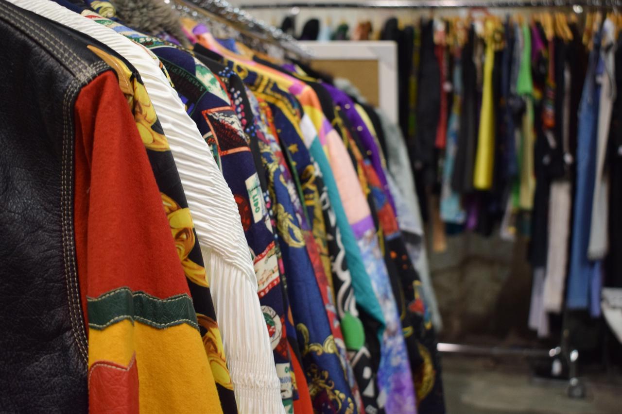 Colorful second-hand and vintage clothing hangs on racks inside a retail shop. (Adobe Stock Photo)