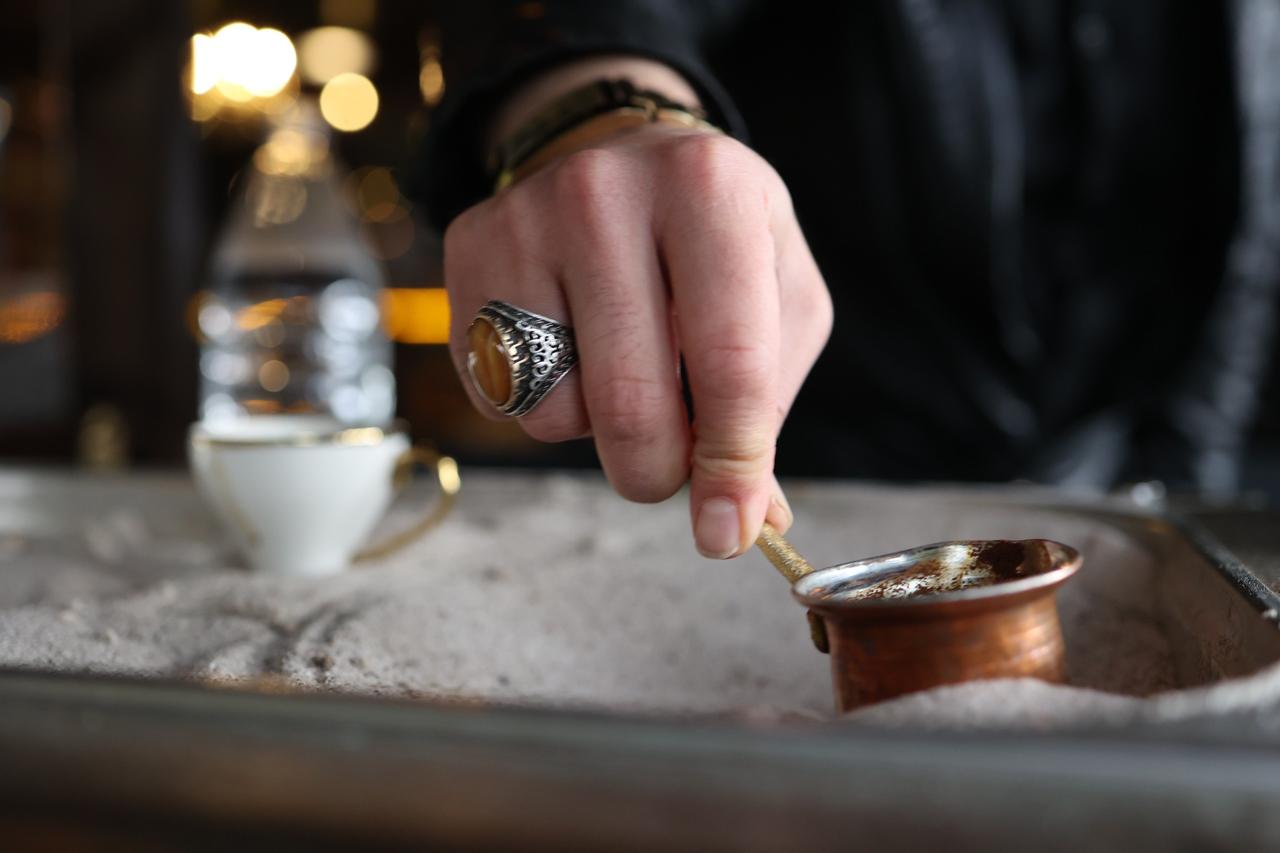 A copper cezve containing Turkish coffee is placed in heated rock salt instead of sand in Cankiri, Türkiye, Oct. 10, 2026. (IHA Photo)