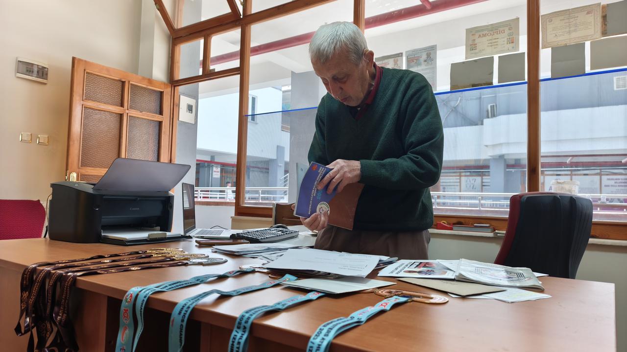 An 84-year-old athlete looks through medals and documents collected during his sporting career as he aims to reach 100 medals in Türkiye, Oct. 11, 2026. (AA Photo)