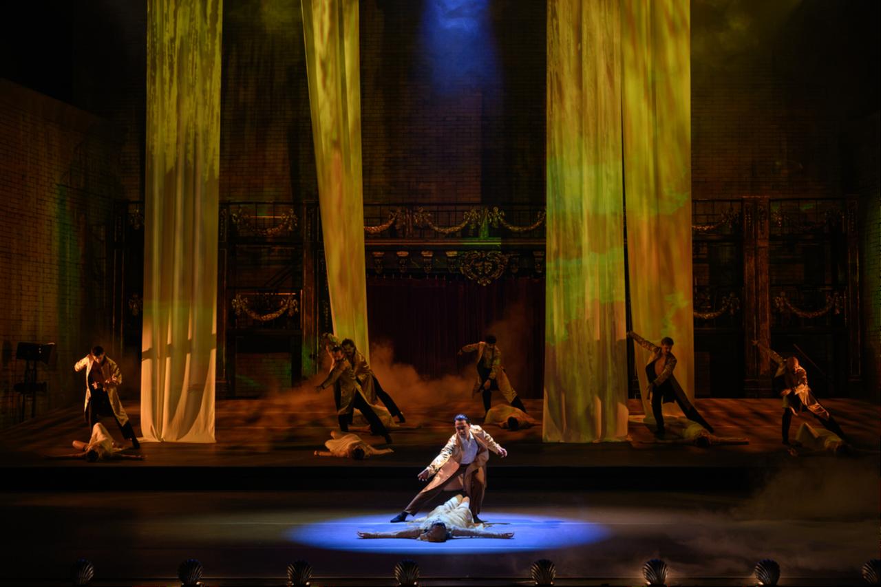 Dancers perform on a stage framed by tall draped curtains and warm lighting during a scene from the "Afife" ballet. (AA Photo)