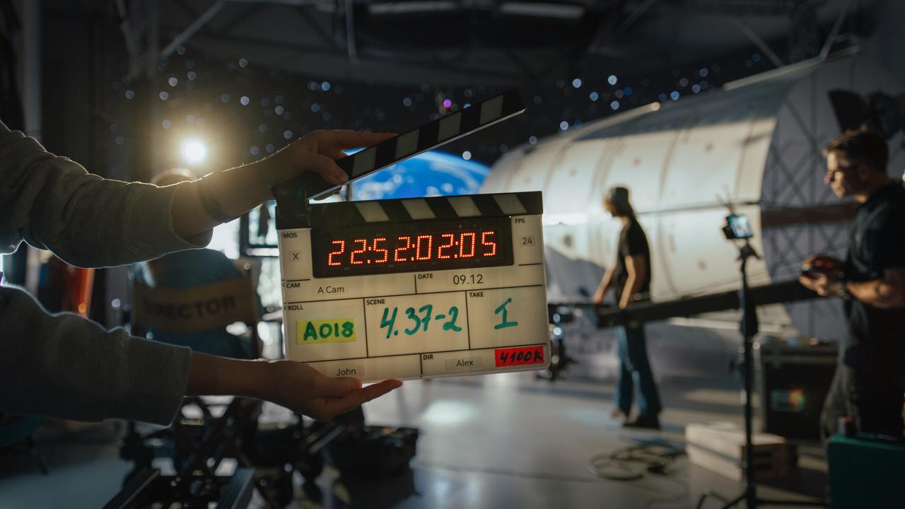 A clapperboard is held in front of a film set during production. (Adobe Stock Photo)