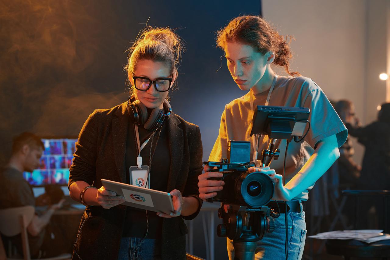 Film production crew members review camera equipment and footage during a shoot on a professional set. (Adobe Stock Photo)