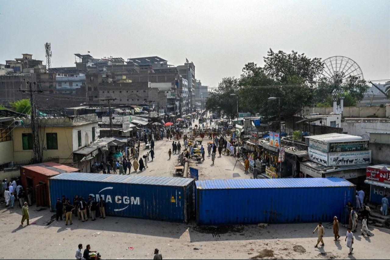 People travel along a road blocked with shipping containers amid ongoing protests by the opposition Pakistan Tehreek-e-Insaf (PTI) party in Peshawar, Oct. 11, 2026. (AFP Photo)