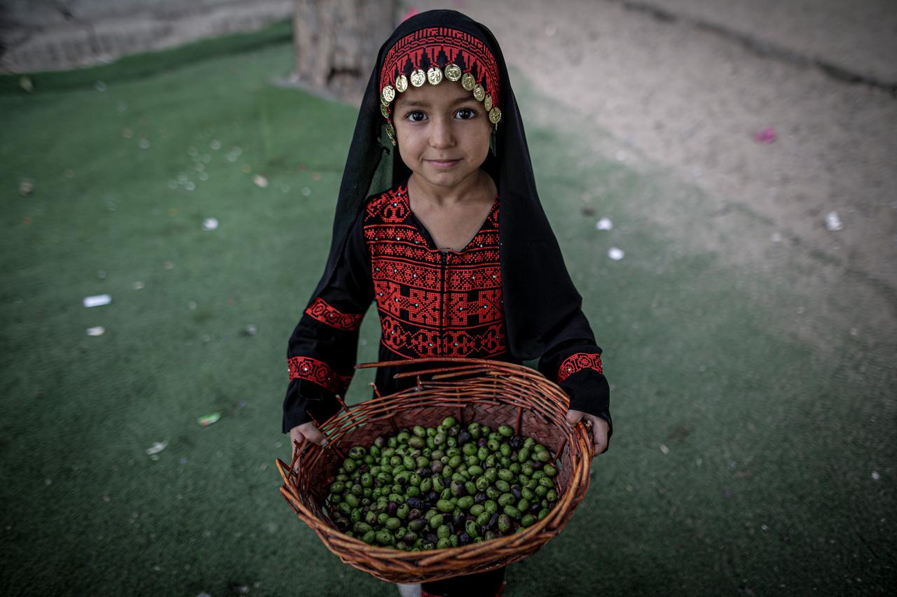 A girl holds a basket of olives as children wearing traditional Palestinian clothing and keffiyehs take part in an event held at an educational point in the Shati Refugee Camp, to pass Palestinian culture and traditions on to younger generations on Palestinian Heritage Day in Gaza City Gaza, Palestine, on October 8, 2026. (AA Photo)