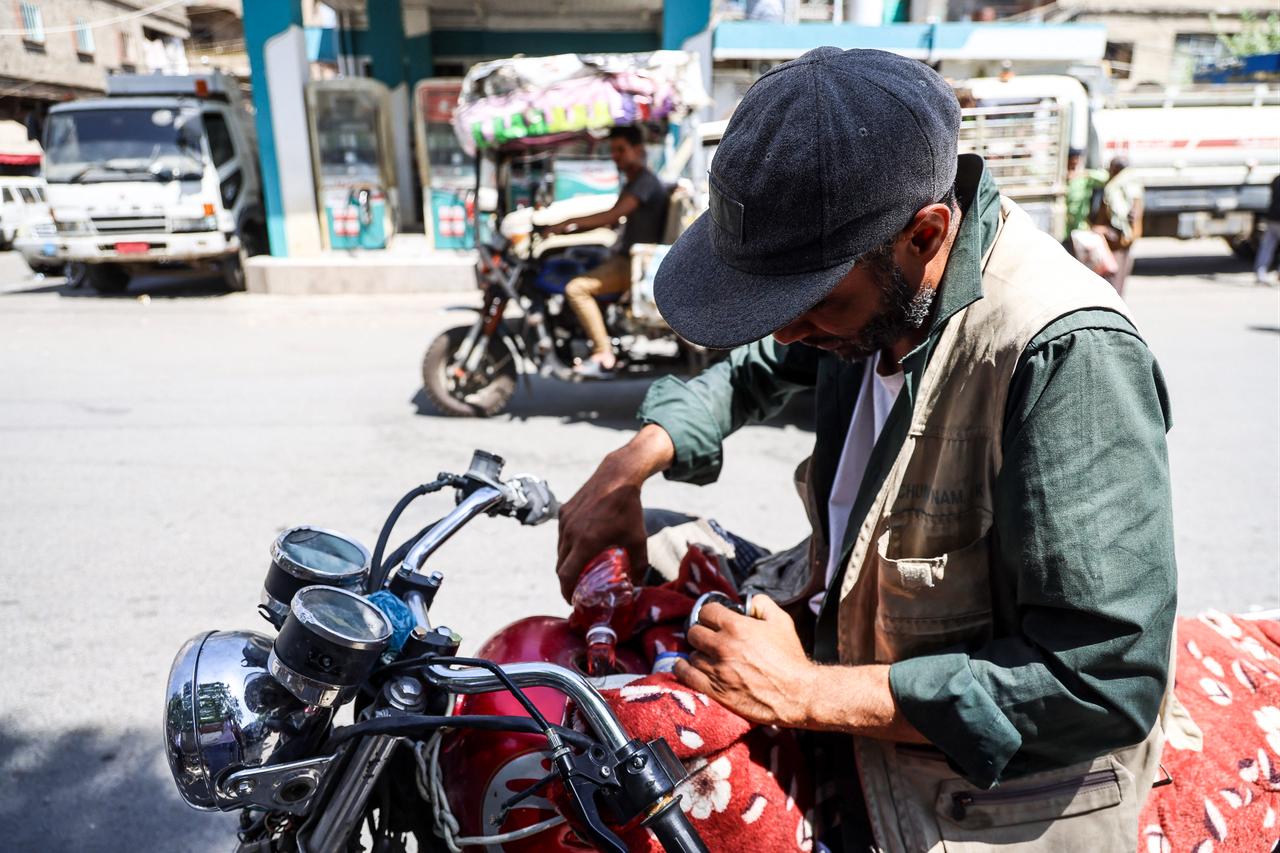 A Yemeni man fills his motorbike with fuel from a plastic bottle he just bought from a vendor along the roadside in the city of Taiz, on October 10, 2026. (AFP Photo)