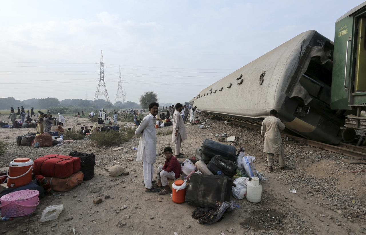 Passengers sit with their belongings next to derailed coaches of the passenger train Rehman Baba Express on the outskirts of Multan on October 13, 2026. (AFP Photo)