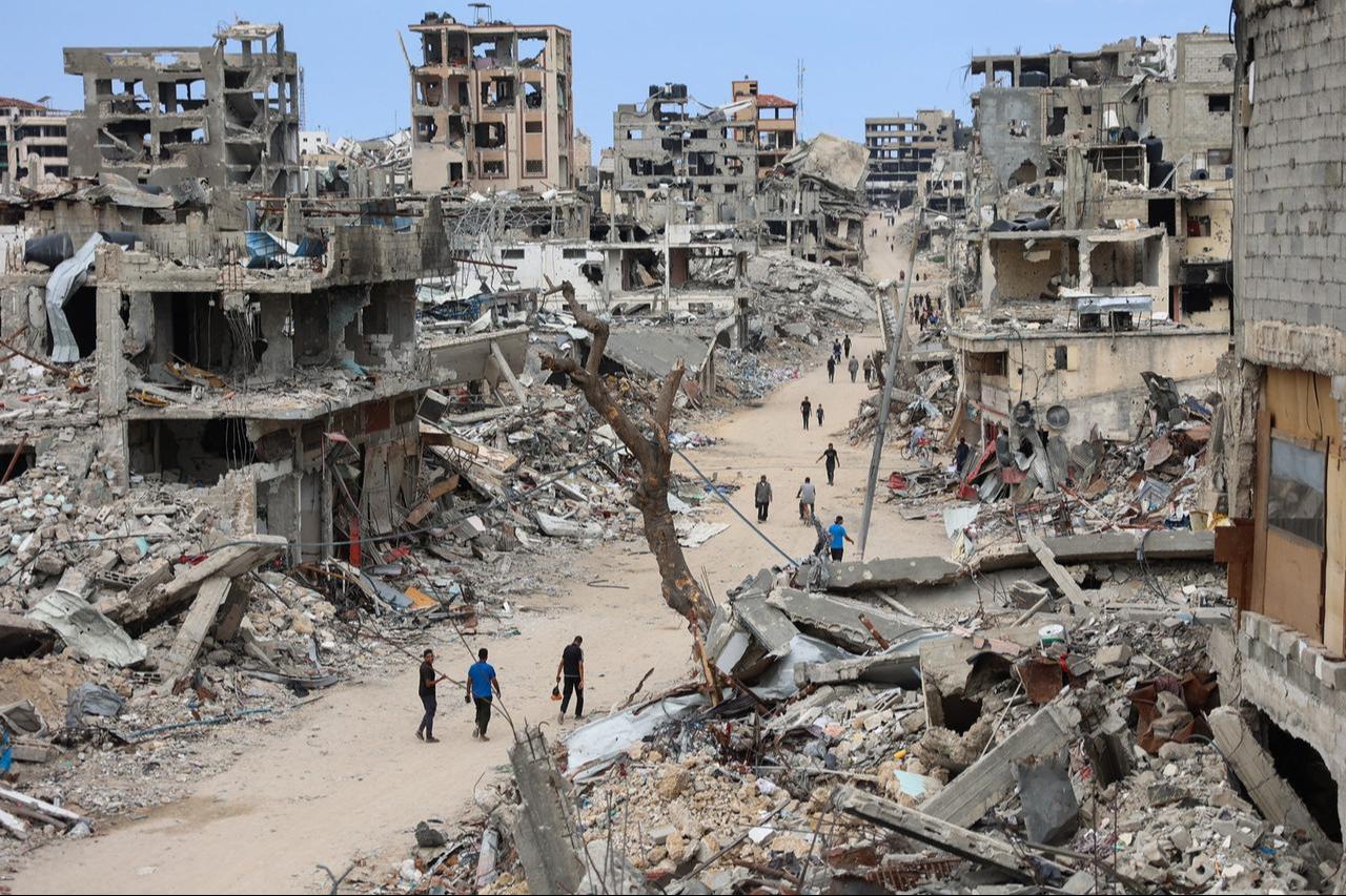 Palestinians walk on a dirt road lined with rubble from destroyed buildings in the Shujaiya neighbourhood of Gaza City on October 7, 2024. (AFP Photo)