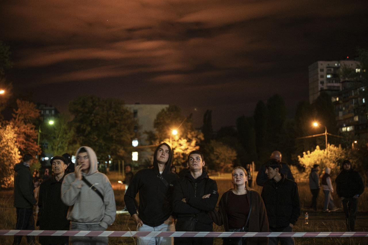 Residents stand behind a barrier at the site of a Russian missile strike at an apartment building in Kyiv on Oct. 14, 2026. (AFP Photo)