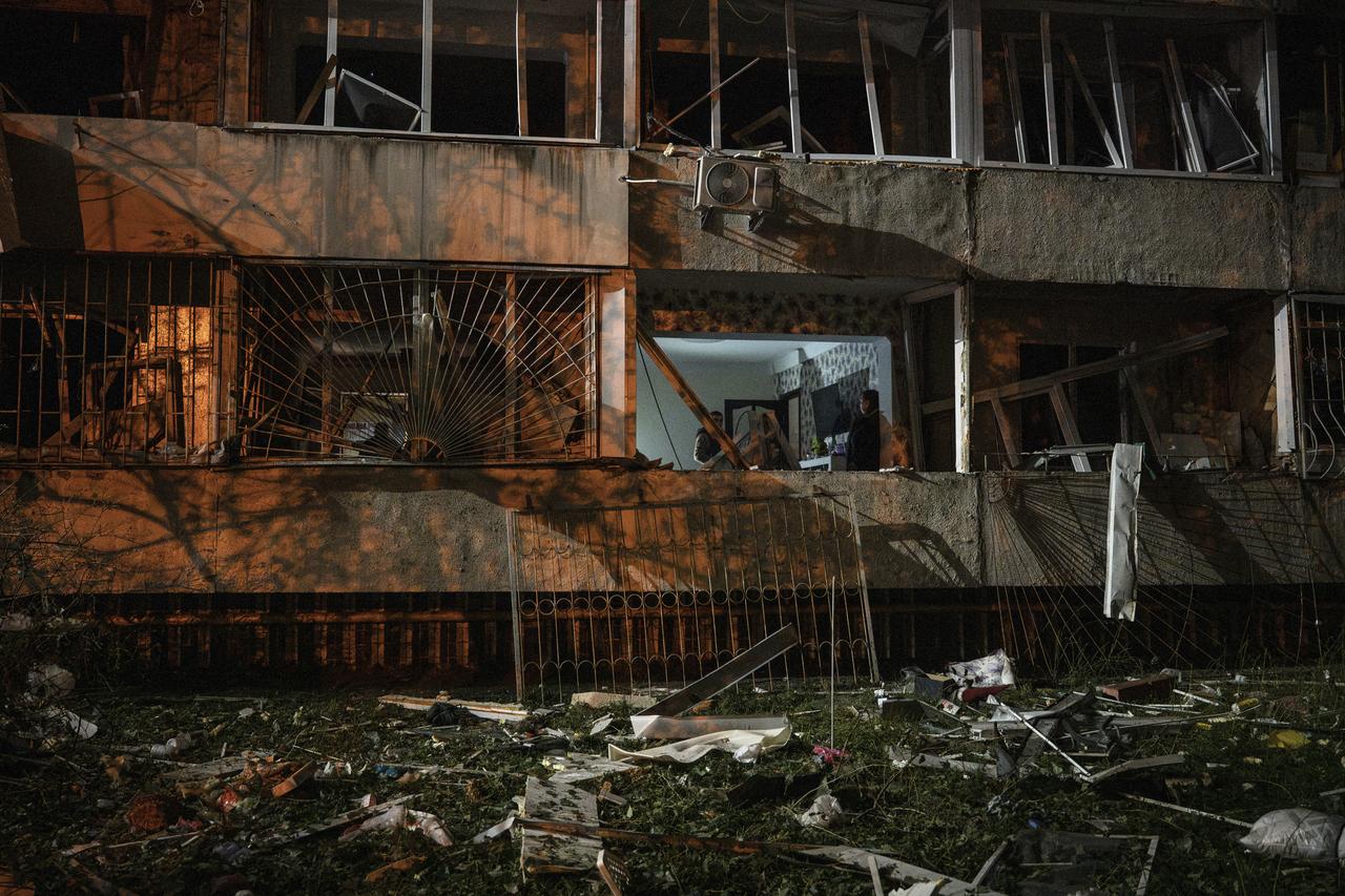 People walk in a damaged flat at the site of a Russian missile strike at an apartment building in Kyiv on Oct. 14, 2026. (AFP Photo)