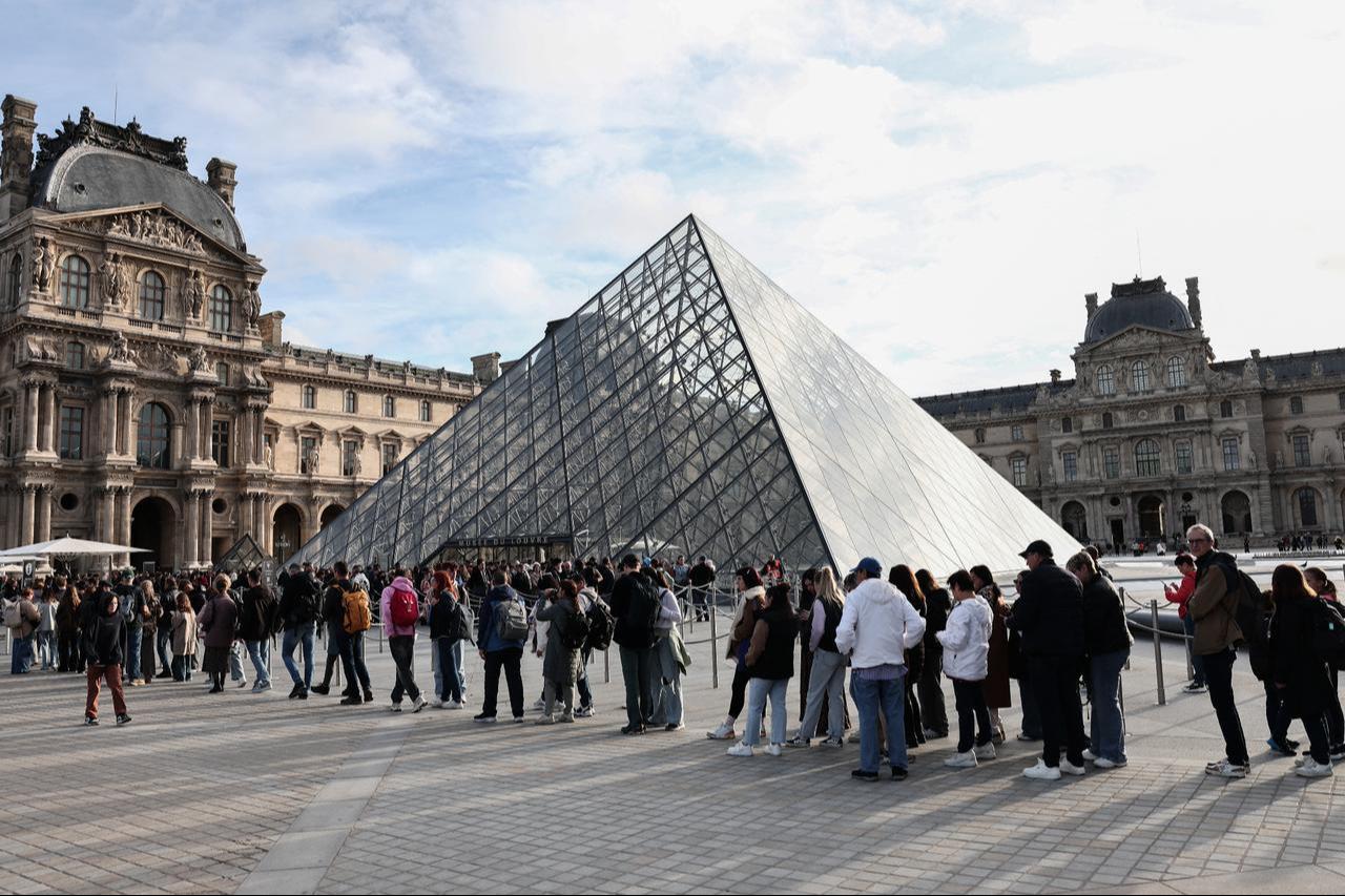 Visitors queue in front of the Pyramide du Louvre, designed by Chinese-US architect Ieoh Ming Pei, with the Louvre Museum in the background in Paris on Oct. 22, 2025. (AFP Photo)