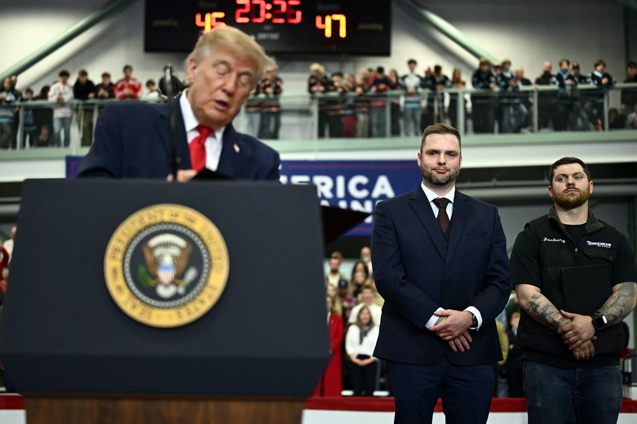 Diesel mechanics Zachary Czubak (R) and Patrick Fleming (C), who were previously charged with and plead guilty to violating the Clean Air Act, watch as US President Donald Trump signs their pardons during a campaign rally at Curtis D. Menard Memorial Sports Center in Wasilla, Alaska, on October 13, 2026. (AFP Photo)