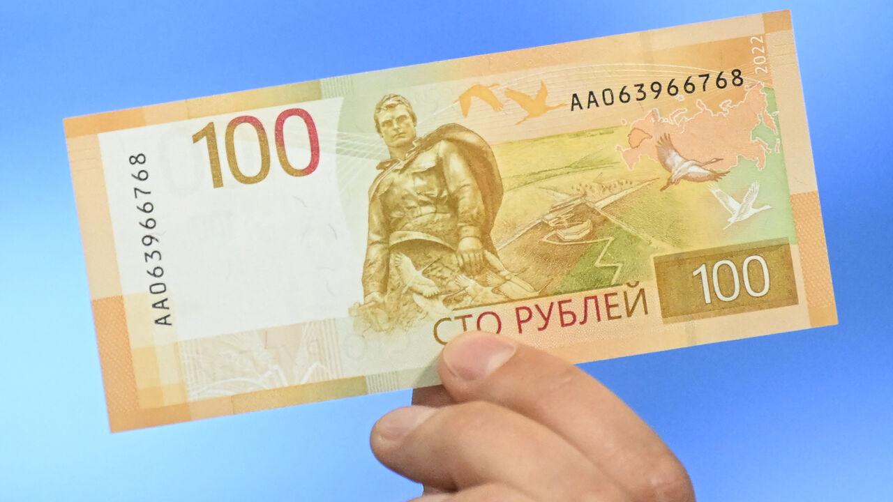 A Russian Central Bank official shows an updated 100-ruble banknote during the official presentation in Moscow on June 30, 2022. (AFP Photo)