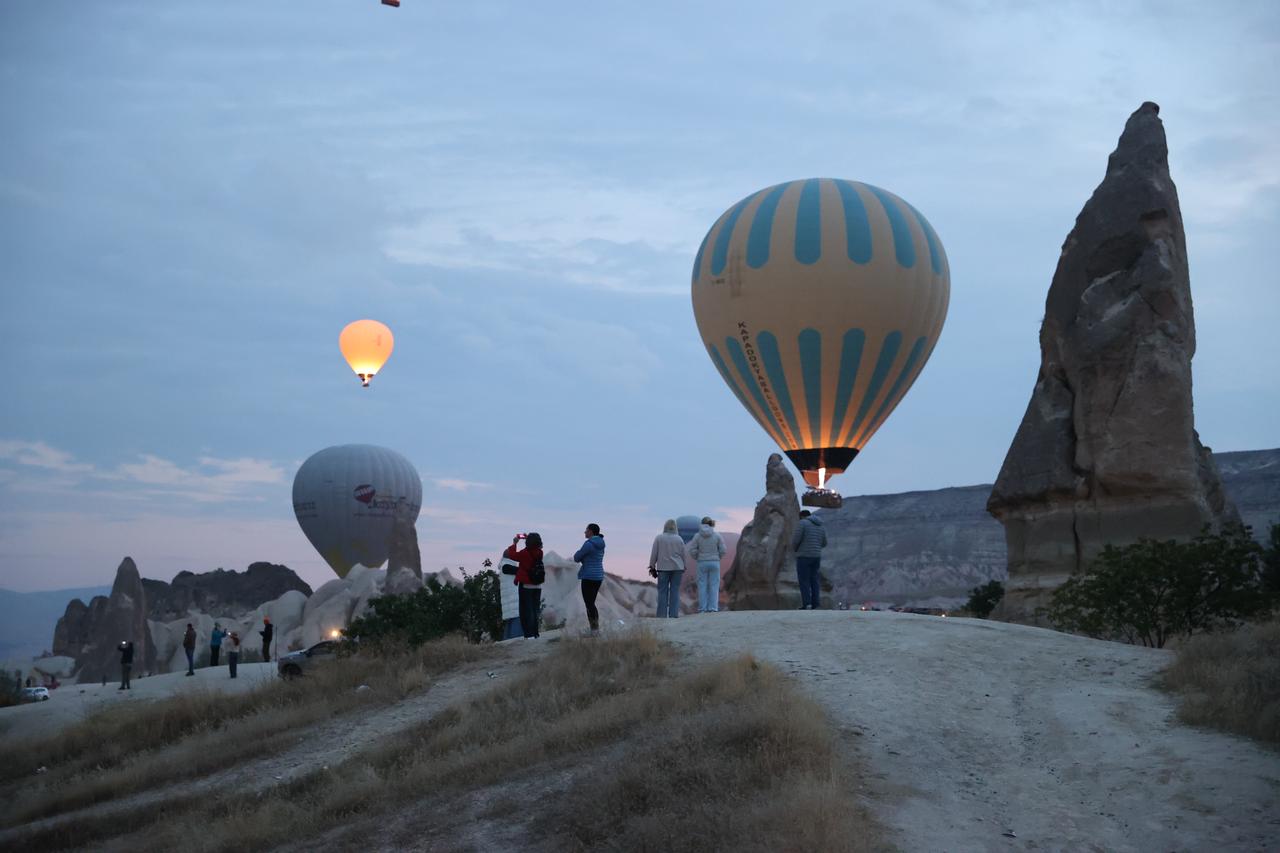 Tourists watch and photograph hot air balloons floating above Cappadocia's distinctive fairy chimneys in Nevsehir, Türkiye, October 16, 2026. (AA Photo)