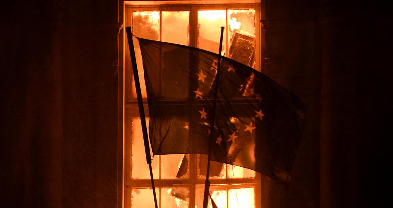 This photograph shows a European Union (EU) flag on the burning city hall after a group of individuals forced entry into the building during ongoing protest action against the "high cost of living", in Limoges, central France on October 17, 2026. (AFP Photo)