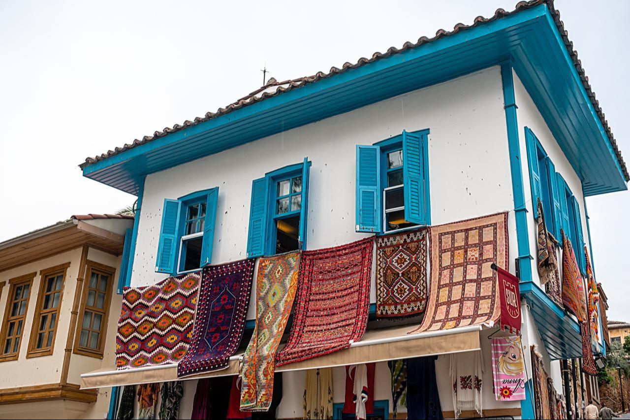 The photo shows old buildings on the streets of Kaleici, the old town in Antalya, Türkiye, with carpets hanging from their windows on April 9, 2023. (Adobe Stock Photo)