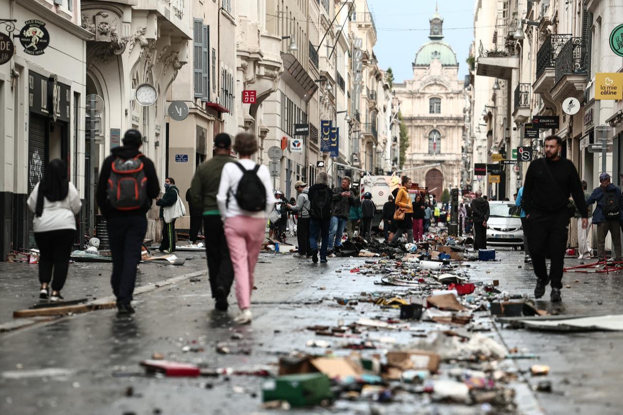 Pedestrians walk along a street covered in debris a day after nationwide protests against the "high cost of living", in Marseille on October 18, 2026. (AFP Photo)