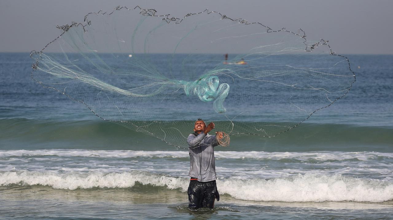 A displaced Palestinian fisherman casts his net on the beach in Deir al-Balah, in the central Gaza Strip, on 20 Nov. 2025. (AFP Photo)
