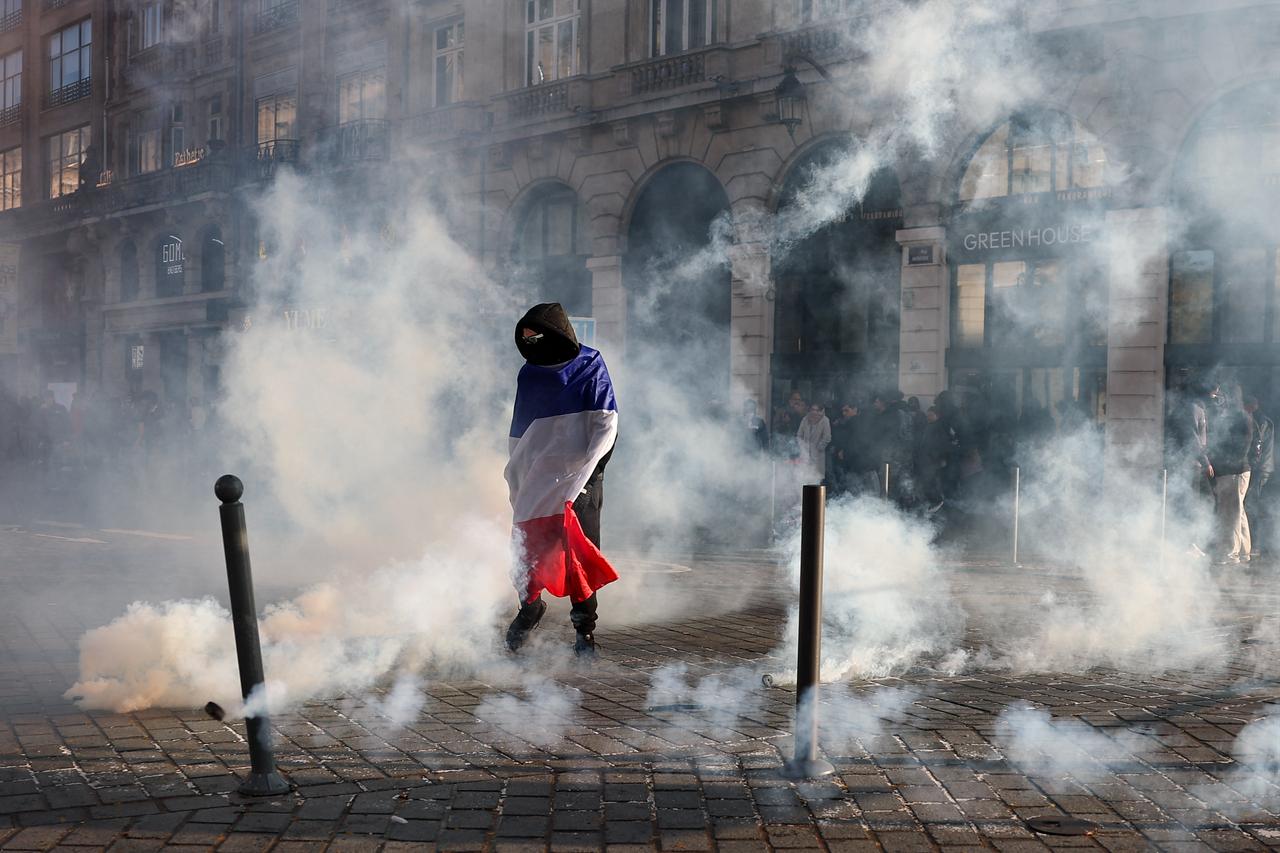 A protester, wrapped in a flag of France, stands in the smoke at Place de l'Opera during ongoing protest action against the "high cost of living", in Lille, northern France, on October 17, 2026. (AFP Photo)