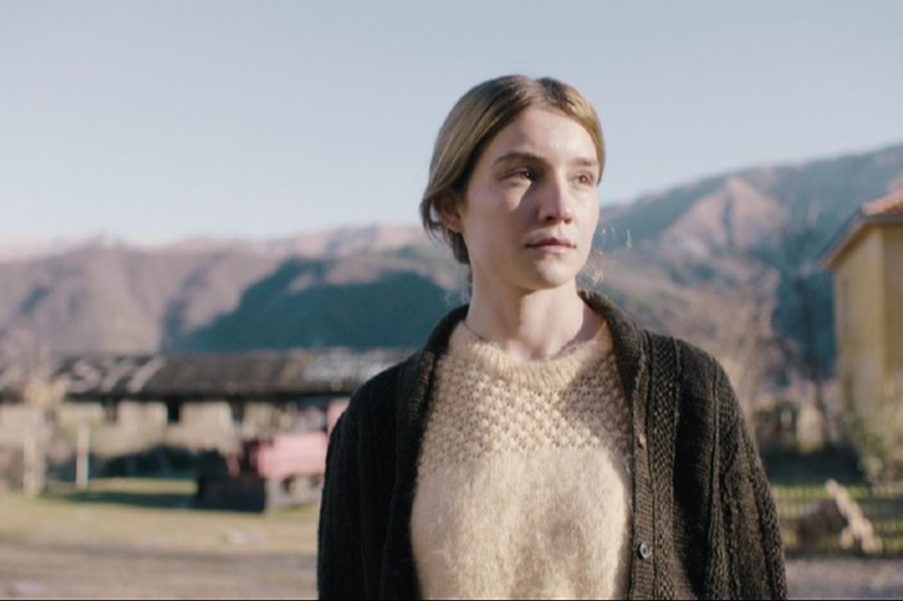 A young woman stands outdoors against a mountainous backdrop in a scene from Albanian filmmaker Lorin Terizi’s feature "Agia". (Photo via Tunnelfilm)