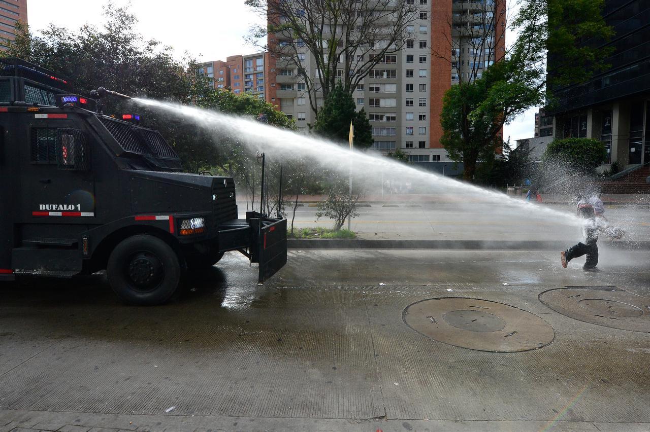A demonstrator is sprayed with water from a police cannon during a protest outside the National Museum against a government order to remove works related to the country’s peace process in Bogota on October 18, 2026. (AFP Photo)