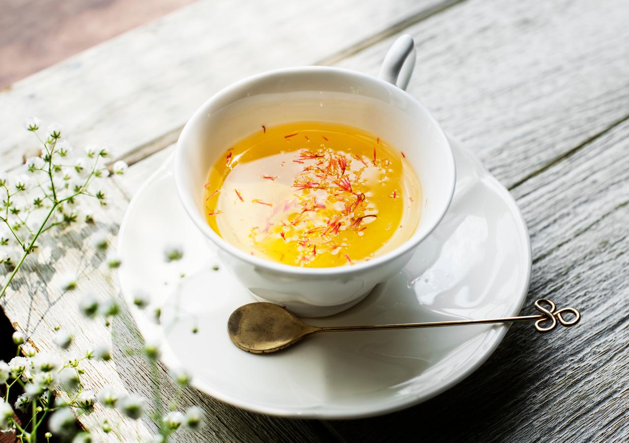 A cup of golden saffron tea garnished with saffron threads is displayed on a wooden table. (Adobe Stock Photo)