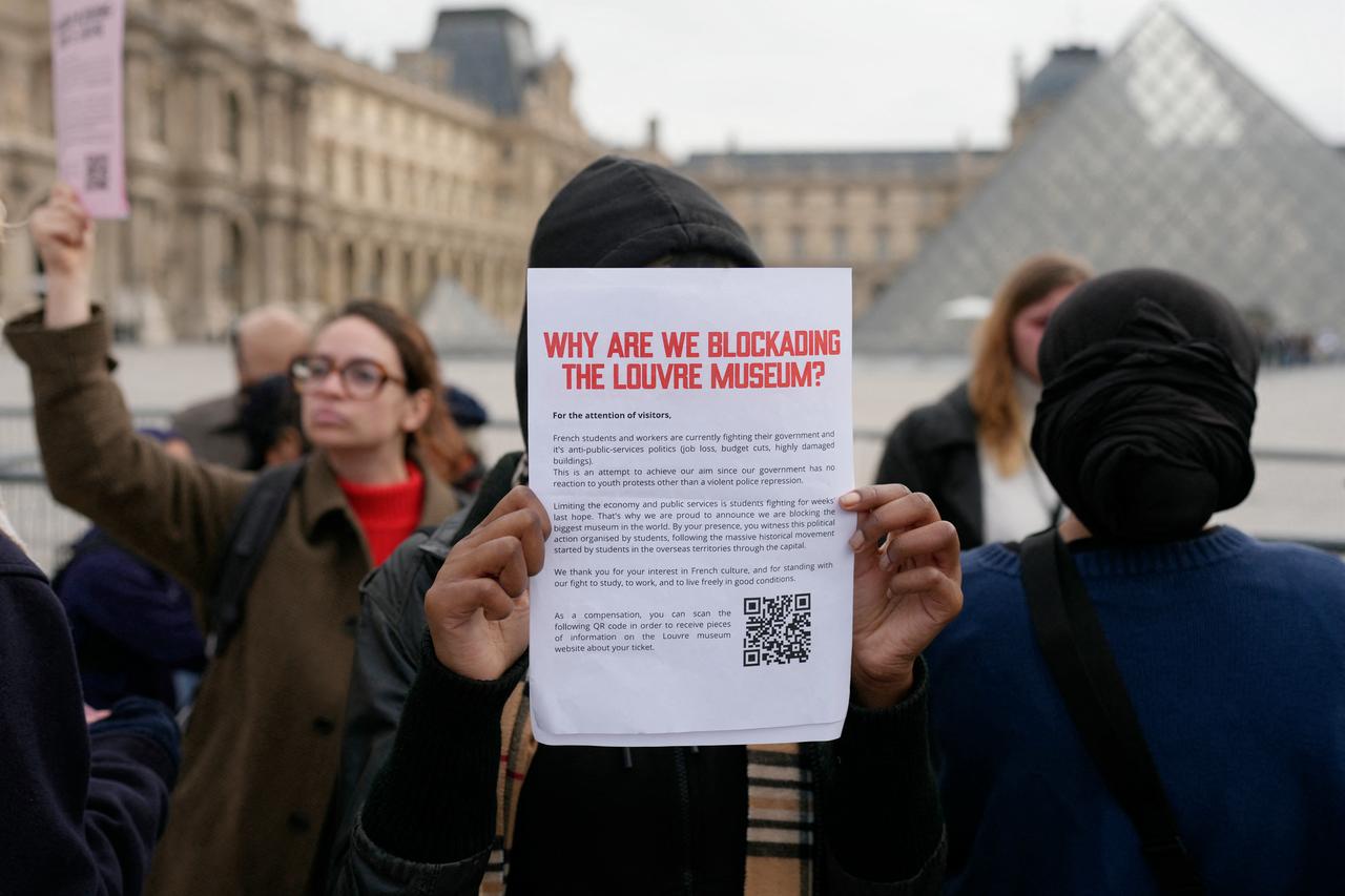 A youth shows a placard informing visitors about the closure as protesters, including students from the Ecole du Louvre, block the entrance to the Louvre Museum to express their “support” for the high school students’ movement and to denounce police repression in Paris on October 19, 2026, two days after riots and looting occurred on the sidelines of nationwide cost-of-living demonstrations. (AFP Photo)
