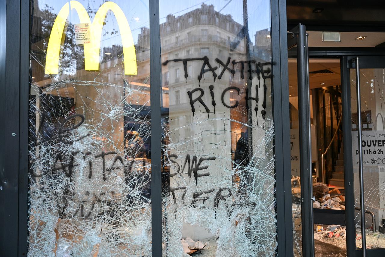 This photograph shows the entrance of a McDonald's fast food restaurant covered in graffiti and damaged a day after nationwide protests against the "high cost of living", in Paris on Oct. 18, 2026. (AFP Photo)