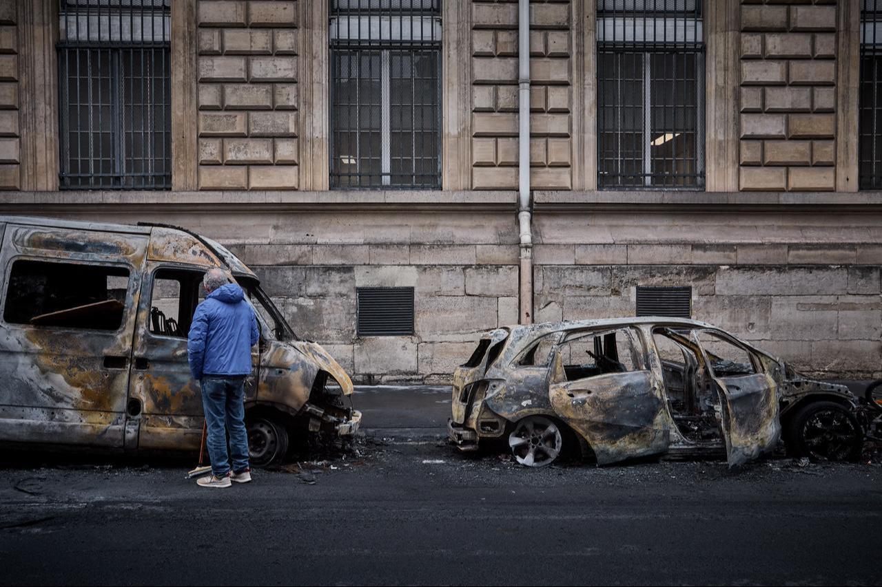 A local resident looks inside a burnt out van on Rue Yves Toudic destroyed after a weekend of protests against the "high cost of living", in central Paris on October 19, 2026. (AFP Photo)