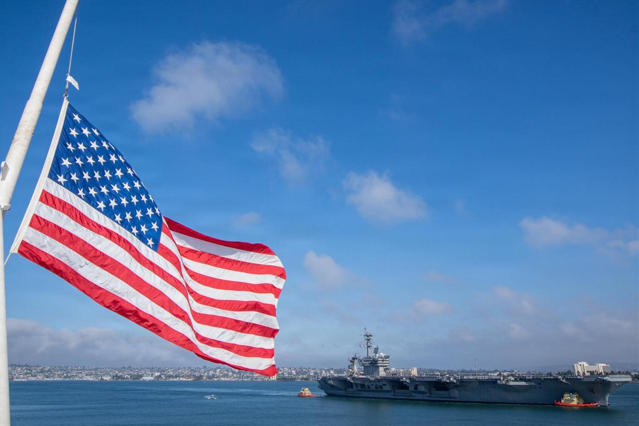 The U.S. flag flies at half-mast aboard Nimitz-class aircraft carrier USS Carl Vinson (CVN 70) while Nimitz-class aircraft carrier USS Theodore Roosevelt (CVN 71) sails into the San Diego harbor, Sept. 11, 2026. (Photo via U.S. Navy)