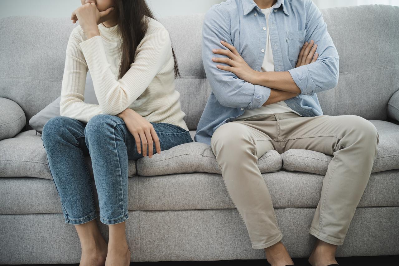 Couple turned away from each other on a sofa. (Adobe Stock Photo)