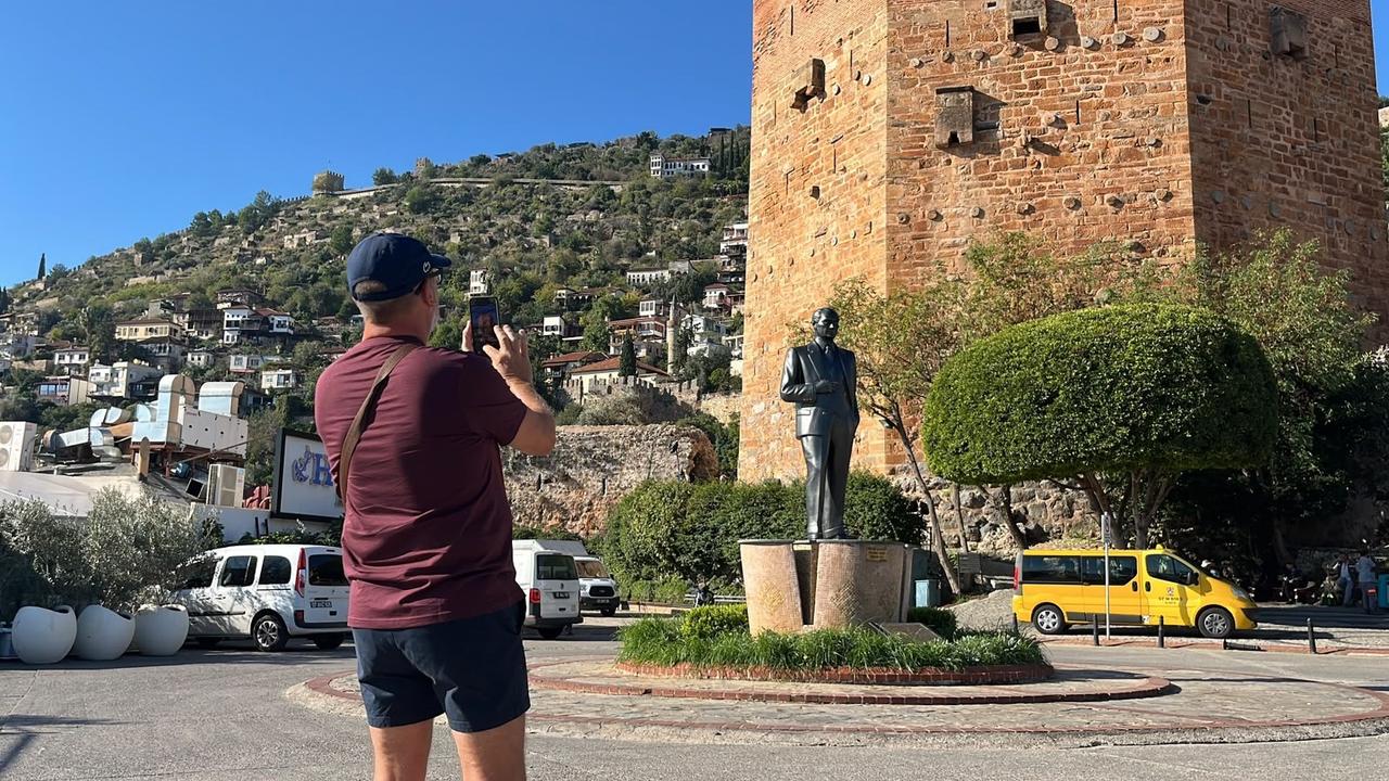 A tourist takes photographs near Alanya's historic Red Tower during a day-long cruise stop in Antalya, Türkiye, Oct. 20, 2026. (IHA Photo)