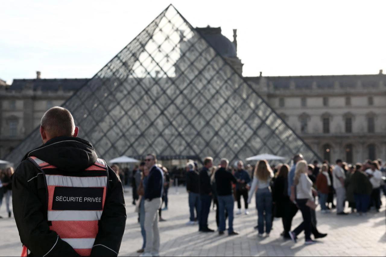 A security guard stands in front of the Pyramide du Louvre, designed by Chinese-US architect Ieoh Ming Pei, with the Louvre Museum in the background in Paris, France, Oct. 22, 2025. (AFP Photo)