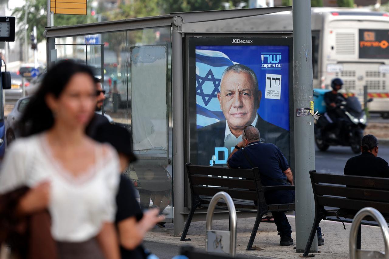 People walk past an election poster bearing a portrait of former military chief and leader of the centrist Yashar party, Gadi Eisenkot, with a message in Hebrew reading "Choosing the righteous way" in Ramat Gan, on Oct. 15, 2026. (AFP Photo)