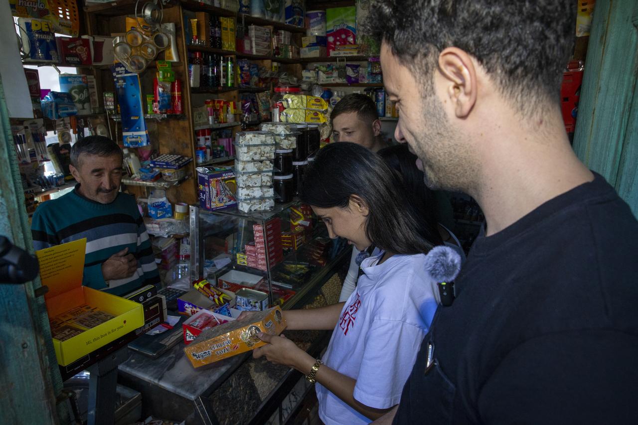Visitors examine a packaged product while speaking with the shopkeeper inside a nearly 120-year-old grocery store operated by the same family for four generations in Türkiye, Oct. 19, 2026. (AA Photo)