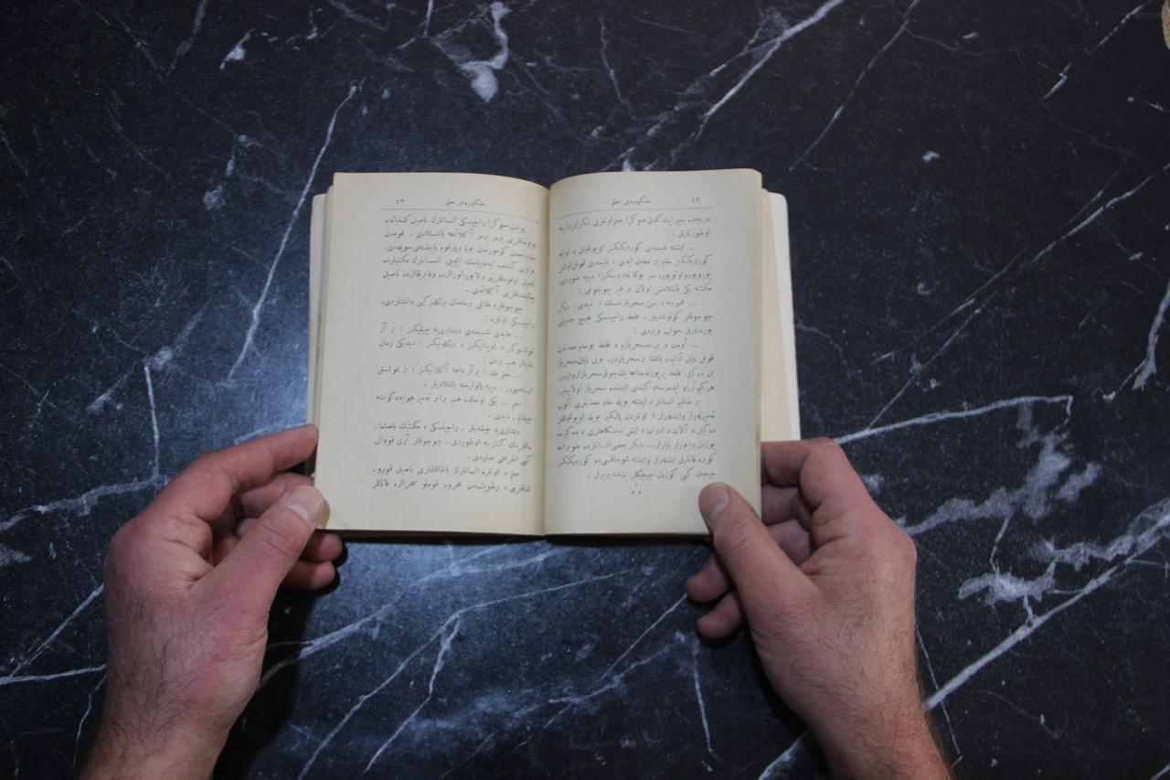 Pages of a rare 1928 edition of Grigory Petrov's The Idealist Teacher, printed in Ottoman Turkish using the Arabic-based script, are displayed at a secondhand bookstore in Erzurum, Türkiye, Oct. 21, 2026. (IHA Photo)